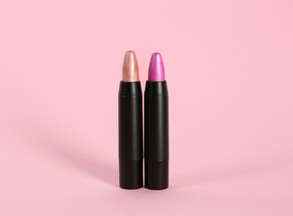 Obraz premium Bright lipsticks in black tubes on pink background