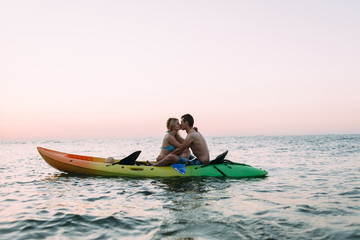 dawn on the ocean, a loving couple kayaking and kissing