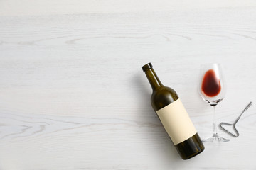 Flat lay composition with bottle of wine and elegant glass on white wooden background. Space for...