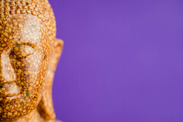 Buddha stone sculpture close-up purple background macro