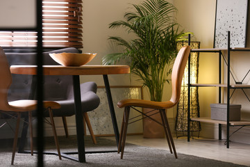 Stylish dining room interior with modern table set and window blinds