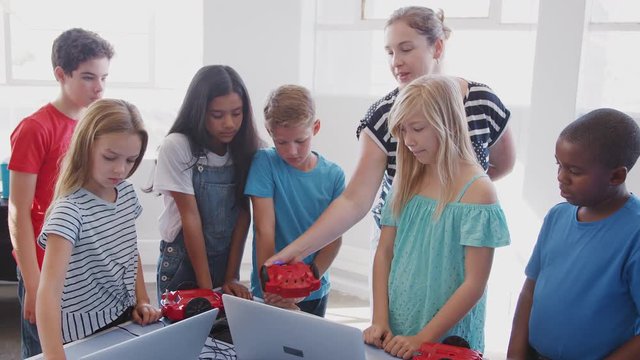 Students With Teacher In After School Computer Coding Class Learning To Program Robot Vehicle