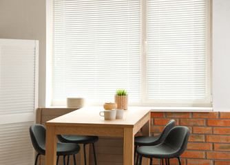 Stylish dining room interior with modern table set and window blinds