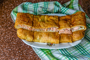 Fresh fried handmade cake with salmon on an old village plate.