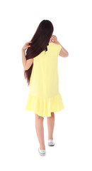 Brunette woman in yellow dress on white background, back view