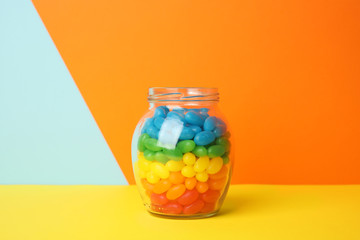 Jar of delicious jelly beans on color background. Space for text