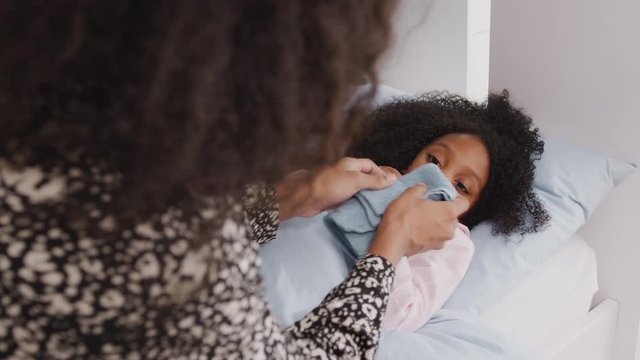Mother Caring For Sick Daughter Ill In Bed With Cold Handing Her A Tissue