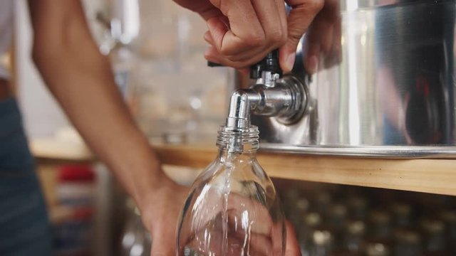 Close Up Of Woman Filling Container With Cider Vinegar In Sustainable Plastic Free Grocery Store