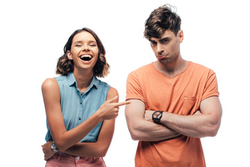 cheerful young woman pointing with finger at offended young man isolated on white