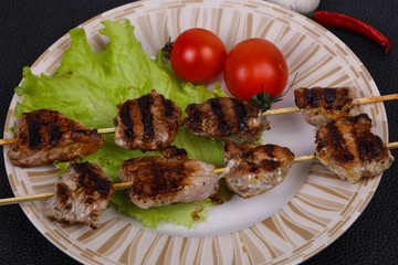 Pork kebab skewers in the plate with salad leaves and tomatoes