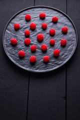 Raspberries on a dark background. Red raspberry on a black plate. Red berries on wooden boards. Top view. Copy space