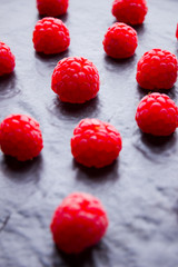 Raspberries on a dark background. Red raspberry on a black plate. Red berries on wooden boards. Top view. Copy space
