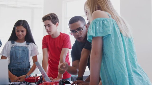 Students With Male Teacher In After School Computer Coding Class Learning To Program Robot Vehicle