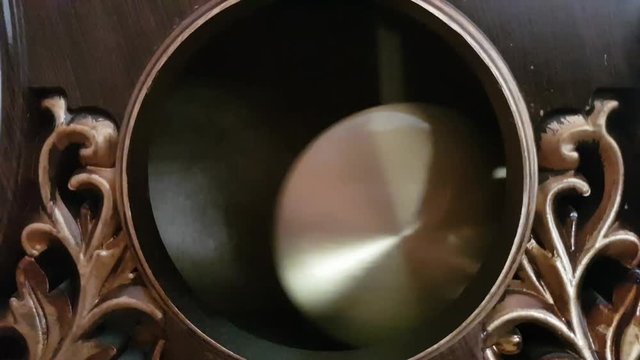 The pendulum of the old clock swings from side to side