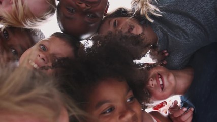 Low Angle Shot Looking Up Into Faces Of Children With Friends Smiling Into Camera