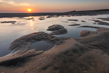 Sunset at the beach. sun just above the horizon on a sky with clouds. calm colors