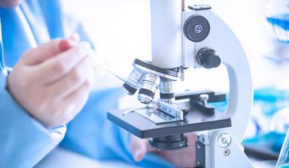 Asian woman scientist, researcher, technician, or student conducted research or experiment by using microscope which is scientific equipment in medical, chemistry or  biology laboratory
