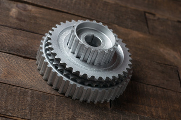 Three metal silver gears lies on old weathered wooden table in workshop