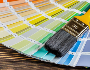 Painter and decorator work table with house project, color swatches, and paint brushes