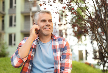 Handsome mature man talking on phone in park