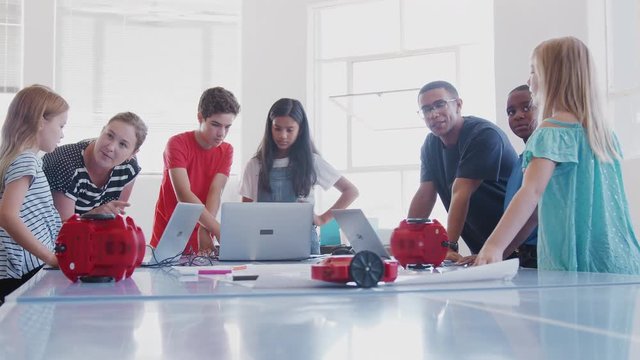Students With Teachers In After School Computer Coding Class Learning To Program Robot Vehicle
