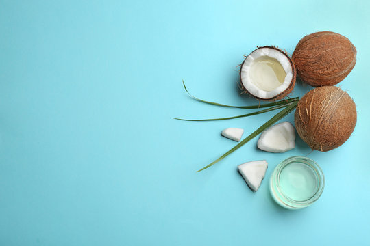 Flat lay composition with ripe coconuts, natural organic oil and space for text on blue background