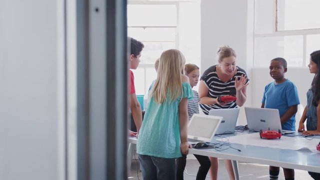 Students With Female Teacher In After School Computer Coding Class Learning To Program Robot Vehicle
