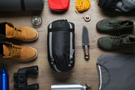 Flat lay composition with different camping equipment on wooden background