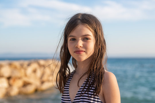 young beautiful girl with wet hair in a swimsuit posing on the beach of the Adriatic Sea