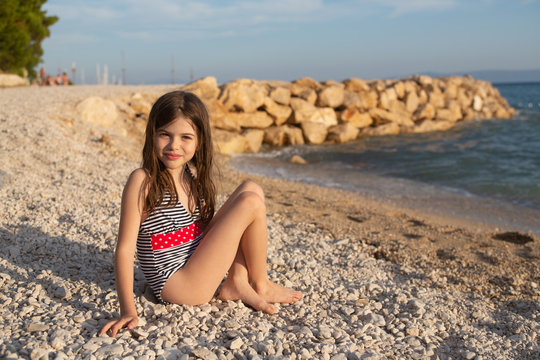 young beautiful girl with wet hair in a swimsuit posing on the beach of the Adriatic Sea