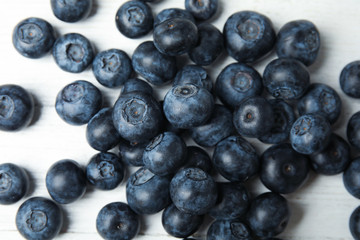 Pile of tasty fresh blueberries on white wooden table, top view