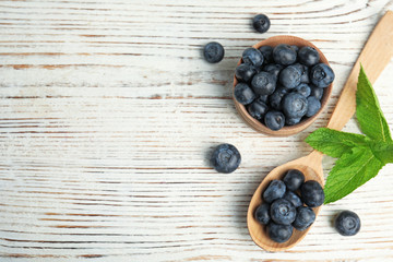 Flat lay composition of tasty blueberries and space for text on white wooden table
