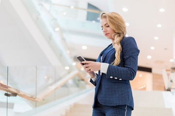 Young businesswoman using her smartphone to browse web content and sending messages