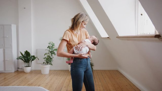 Loving Mother Holding Sleeping Newborn Baby At Home In Loft Apartment