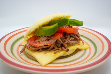 front view of an Arepa filled with shredded meat tomatos and avocado