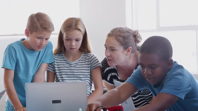 Students With Female Teacher In After School Computer Coding Class Learning To Build Robot Vehicle