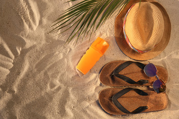 Flat lay composition with stylish beach accessories on sand. Space for text