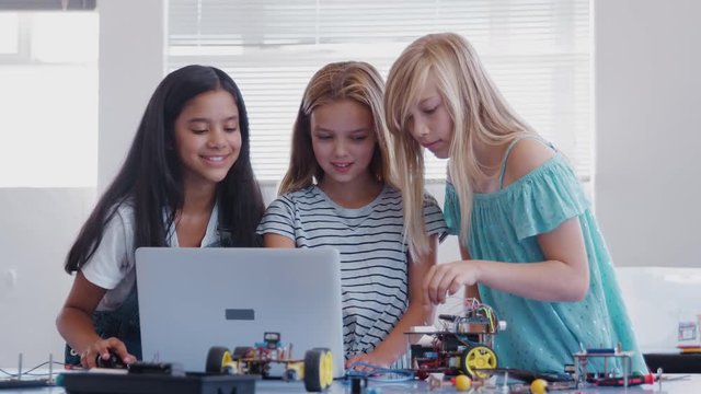 Three Female Students Building And Programing Robot Vehicle In After School Computer Coding Class 