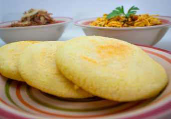 Arepas with shredded meat and chicken in the background