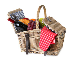 Wicker picnic basket with wine and different products on white background