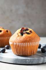 Stone board with blueberry muffins on light table, closeup view. Space for text