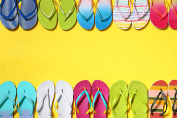Different flip flops and space for text on yellow background, flat lay. Summer beach accessories