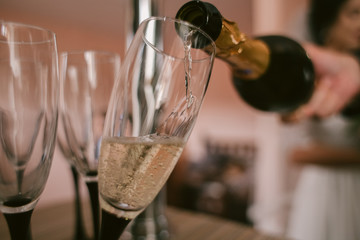 Champagne is poured into a glasses. Concept for drink and beverage. Blur background.