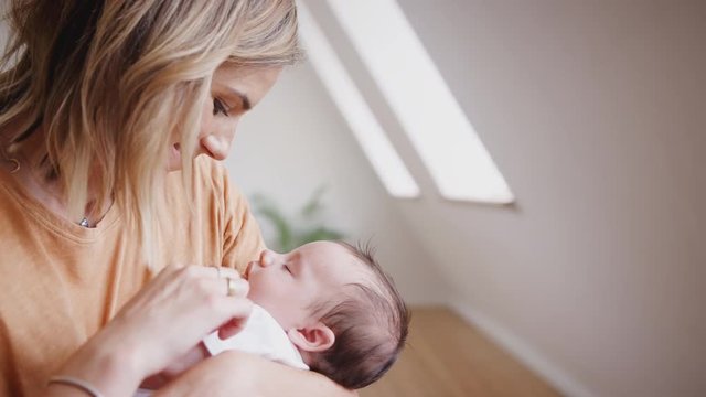 Loving Mother Holding Sleeping Newborn Baby Son At Home In Loft Apartment