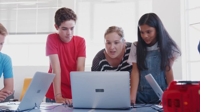 Students With Female Teacher In After School Computer Coding Class Learning To Program Robot Vehicle