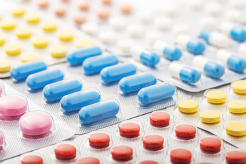 Heap of medical pills in white, blue and other colors. Pills in plastic package. Concept of...
