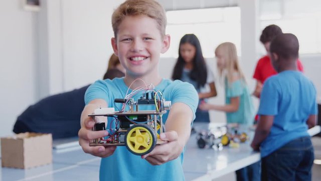 Portrait Of Male Student Holding Robot Vehicle In After School Computer Coding Class 