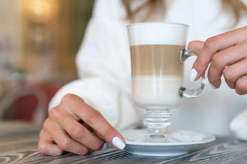 Fototapeta na wymiar girl holds glass latte coffee in hands. Three Layer Latte
