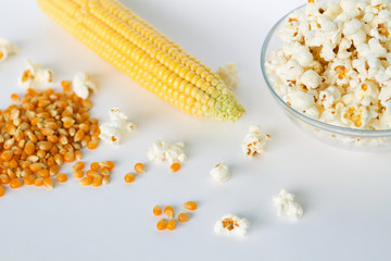 popcorn in a bowl with yellow corn grains and cob corn isolated on white background top view