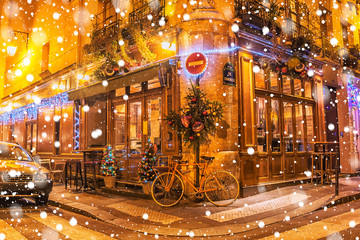 Typical Parisian cafes, decorated for Christmas holidays on a winter night in Paris, France.